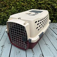 Front angled view of the pet crate showing the metal wire door, locking mechanism, and ventilation holes on the side.