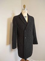 Front view of dark charcoal grey men's Reiss wool coat on mannequin showing double breasted button closure and peak lapel.