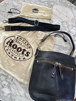 Full lot laid out: leather bag, two dust bags and woven strap