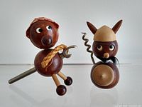 Front view of two teak Viking barware figurines: one with corkscrew tail and shield, the other with metal bottle opener arm and cloth head covering.