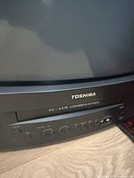 Close-up of Toshiba brand logo and TV/VCR combo label on front panel with control buttons visible below the screen