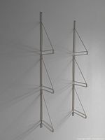 Two white painted steel rod vintage wall shelf brackets mounted on a blank wall showing overall shape and size.
