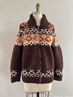 Front view of brown knit wool sweater with red and cream geometric heart and diamond pattern, and front zipper