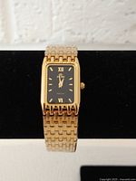 Front view of the Fiori Elegance women's rectangular gold tone fashion watch on display stand, showing black dial with gold markers.