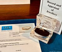 Ring and appraisal certificate displayed together on blue cloth
