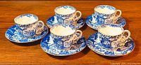 Five pairs of Royal Crown Derby Mikado demitasse cups and saucers arranged in two rows on wooden surface.