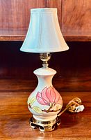 Full front view of lamp showing porcelain body, floral design, brass-tone base, shade