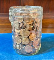 Front view of a glass jar filled with vintage pennies, showing the jar's shape and the coins inside.