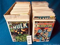 Two short cardboard boxes filled with bagged comics, front shows The Incredible Hulk #261 and Marvel Presents: Bloodstone.