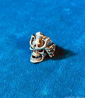 Angled shot showing detailed skull face with vampire teeth and ornate Shogun helmet design on sterling silver biker ring.