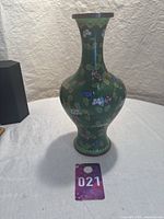 Full front view of the 11 inch green floral Cloisonne vase showing bulbous base and narrow neck with detailed enamel floral designs and bronze/copper rim.