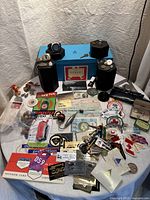 Overview image of the assorted collectibles and memorabilia arranged on a table, showing rings, pins, patches, cards, pipes, and containers.