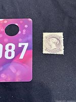 Full image of the 1860 Nova Scotia 2 cent Queen Victoria profile postage stamp on black background with reference card.