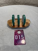 Front view of vintage Noritake lusterware toast rack showing four green vertical slots on a gold-tone base with scalloped edge.