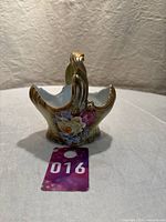 Front view of the porcelain basket showing hand-painted floral design and gold accents on handle and edges.