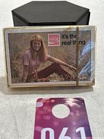 Front side of sealed playing card deck featuring a woman and the Coca-Cola logo with slogan "it's the real thing".