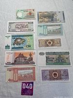 Top view of a variety of world paper money including denominations from Vietnam, Laos, Cuba, and Myanmar, displayed flat on a white cloth background.