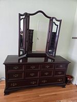 Full view of solid mahogany dresser with attached three-panel mirror showing overall condition and style.