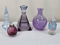 Lot of five assorted decorative glass bottles displayed on a flat surface against a plain background.