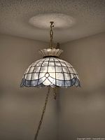 Full view of the hanging swag lamp suspended from the ceiling by an 18-inch metal chain, showing the dome-patterned translucent shade and supporting crown.