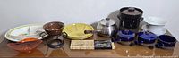 Full assortment of kitchenware items including bean pot, Franciscan floral platter and bowl, fondue pot with forks, three French onion soup bowls (one missing lid), and assorted plates and bowls in various colors