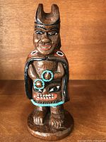 Full front view of Haida ceramic Medicine Man figurine showing headdress, facial details, cape, and base.