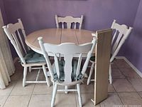 Overall view of round table with two leaves removed and four chairs in place