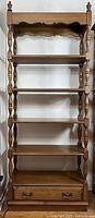 Front view of Vilas maple bookshelf showing five shelves and bottom drawer with brass handles
