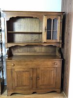Full view of the assembled two-piece maple wood hutch showing the upper display cabinet and lower storage cabinet.