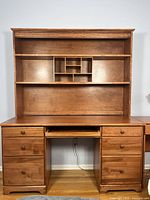 Front view of wood desk with attached hutch showing shelves and drawers