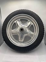 Close-up image of a 15 inch flat-free wheelbarrow wheel showing black tire and silver rim.