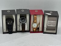 Four ladies watches displayed in original boxes showing overall lot contents.