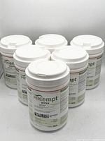 Photo showing six white plastic containers of PREempt wipes with flip-top lids arranged in two rows.