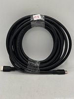 Coiled black 25-foot HDMI cable with identification tag attached.