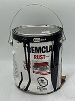 Tremclad Rust Paint Gloss Black 3.78L can with damaged tin and black paint drips visible