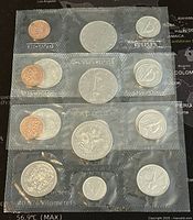 Three Canadian proof-like coin sets in sealed plastic sleeves with different denominations visible.