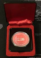 Silver Canadian dollar coin in protective case inside red velvet-lined black presentation box
