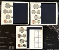 Overview of all three specimen coin sets in protective cases showing coins and certificates.