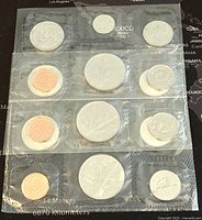 Three Canadian coin sets from 1983, 1984, and 1985 sealed in plastic sheets, visible individual coins with proof-like surfaces.