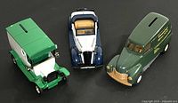 Photo showing three die cast toy banks modeled as vintage vehicles together: green/white 1917 Ford Model T Delivery Truck Van, blue/white 1937 Chevy Convertible, and green 1950 Chevy Panel Truck with coin slots visible on top.