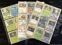 Full spread of 27 assorted Pokémon trading cards displayed on a dark surface with visible text and artwork.