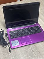 Purple Dell Inspiron 17R laptop with screen closed and AC power adapter beside it.