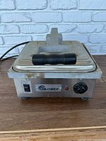 Front view of the closed Globex grill press showing the top handle, front power switch, brand logo, and temperature knob.