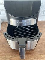 Gourmia air fryer open showing removable cooking basket with metallic body and black handle.