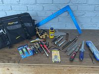 Photo showing entire tool lot with AWIP HP branded soft tool bag, hand tools including screwdrivers, reciprocating saw blades, carpenter's square, gloves, and other miscellaneous tools.