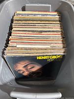 Bin of more than 60 vintage vinyl records stacked vertically, showing edges and spines with album covers worn and aged