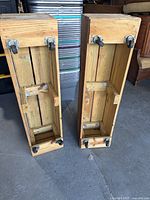 Pair of wooden rolling benches standing upright showing wheels underneath