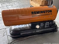 Side view of the Remington Model 75 kerosene heater showing orange metal heat shield and black base.