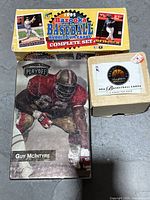 Photo showing 1995 Bazooka Baseball Bubblegum Cards complete set box, Playoff NFL football card box with Guy McIntyre image, and SkyBox NBA basketball cards box.
