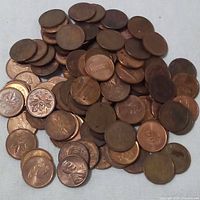 Top view of 100 mixed Canadian and American pennies showing maple leaf design and Lincoln Memorial.